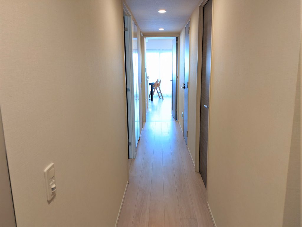 【室内廊下】 玄関からリビングに続く室内廊下部分の様子です。明るいブラウンの床材とホワイトのクロスがスタイリッシュな印象を演出しています。