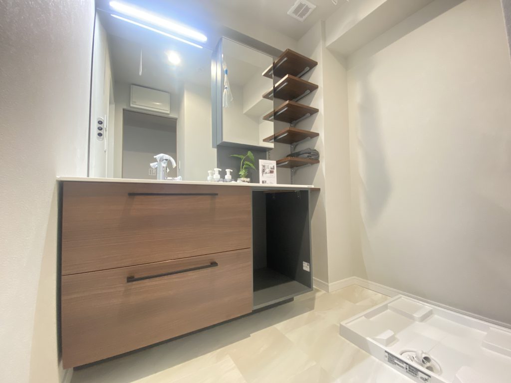 【洗面】 TOTOの高級洗面シリーズ「エスクア」を使用。タッチレスハイネックスウィング水栓（センサースイッチ・ホース付）、サイレントレール仕様のキャビネットが特徴です。造作したオープン棚も同色でコーディネ