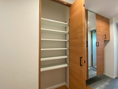 【玄関】 シューズボックス横にある大型の廊下収納の様子です。棚板は可動式なので、収納するものに合わせて高さが自由に変えられます。