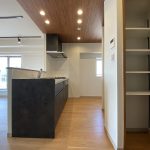 【キッチンの天井部分】 空間が引き締まるダークカラーのキッチンを採用、天井は木目とダウンライトでレストランのような雰囲気を演出しています。